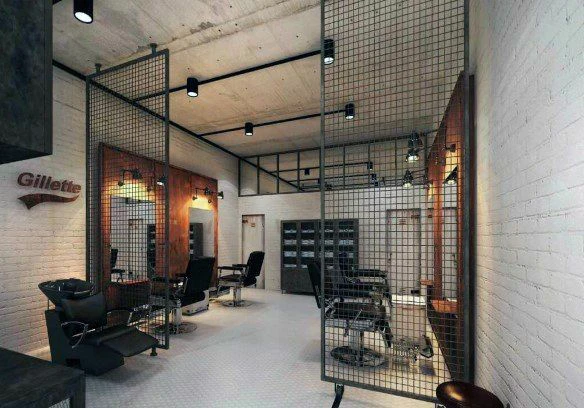 نمای داخلی یک آرایشگاه با سبک صنعتی؛ دیوارهای سفید آجری، پارتیشنهای توری فلزی، صندلیهای سلمانی مشکی و نورپردازی سقفی روی پسزمینه روشن.